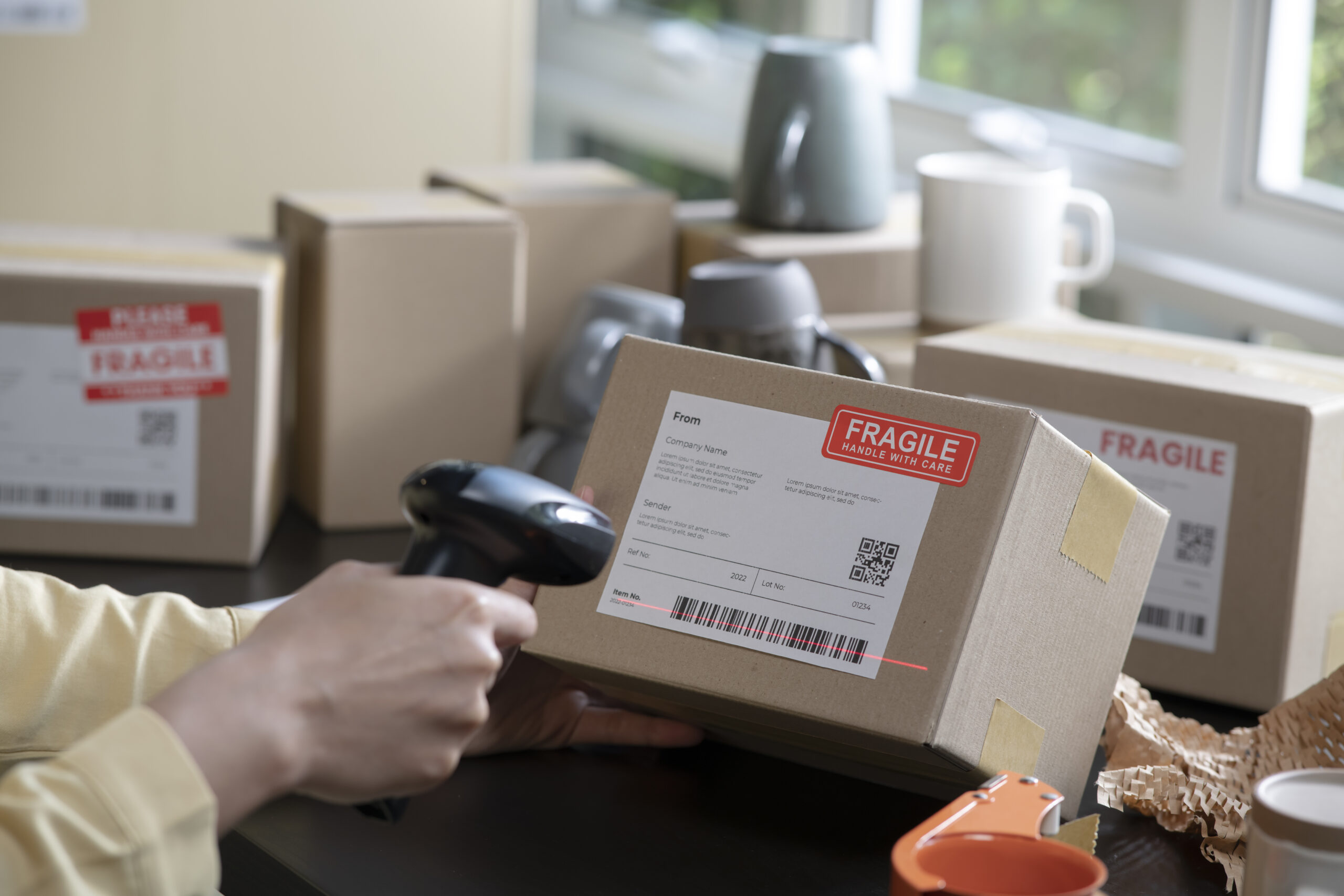 Closeup image of hands scanning barcode on delivery parcel. Worker scan barcode of cardboard packages before delivery at storage. Woman working in factory warehouse scanning labels on the boxes with barcode scanner.